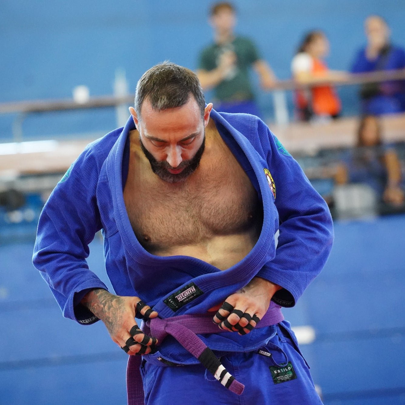 Man in a blue bjj gi preparing to compete using Sticky Grips Finger Tape