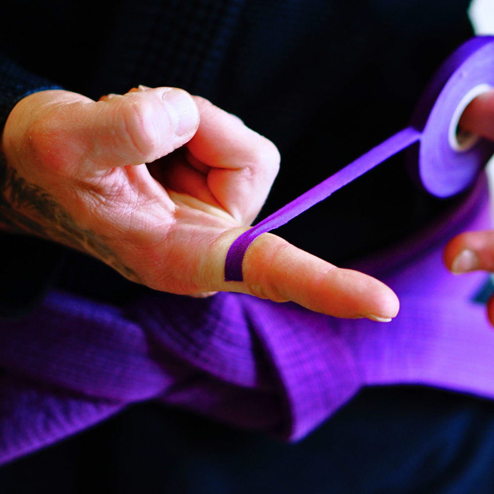 Athlete applying Sticky Grips purple 8mm BJJ finger tape low stretch refill 10m during training